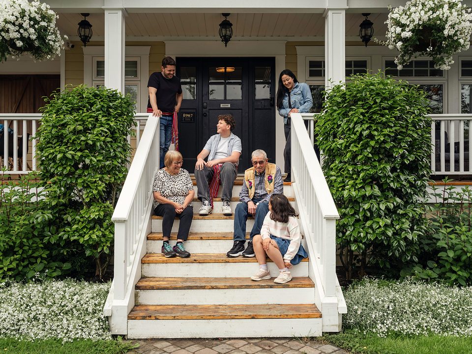 A family relaxing together on the front porch steps of their home